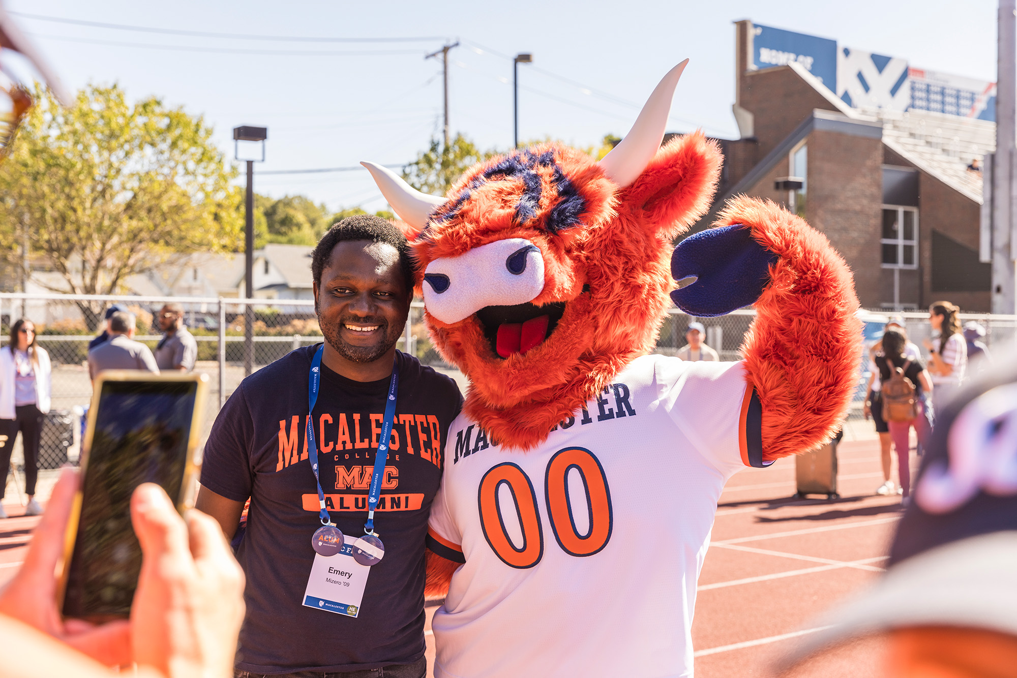 A Macalester alum poses with the highland cow mascot.