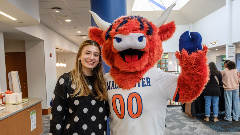 Macalester's mascot, Coo, waves while posing with a student in the Campus Center.