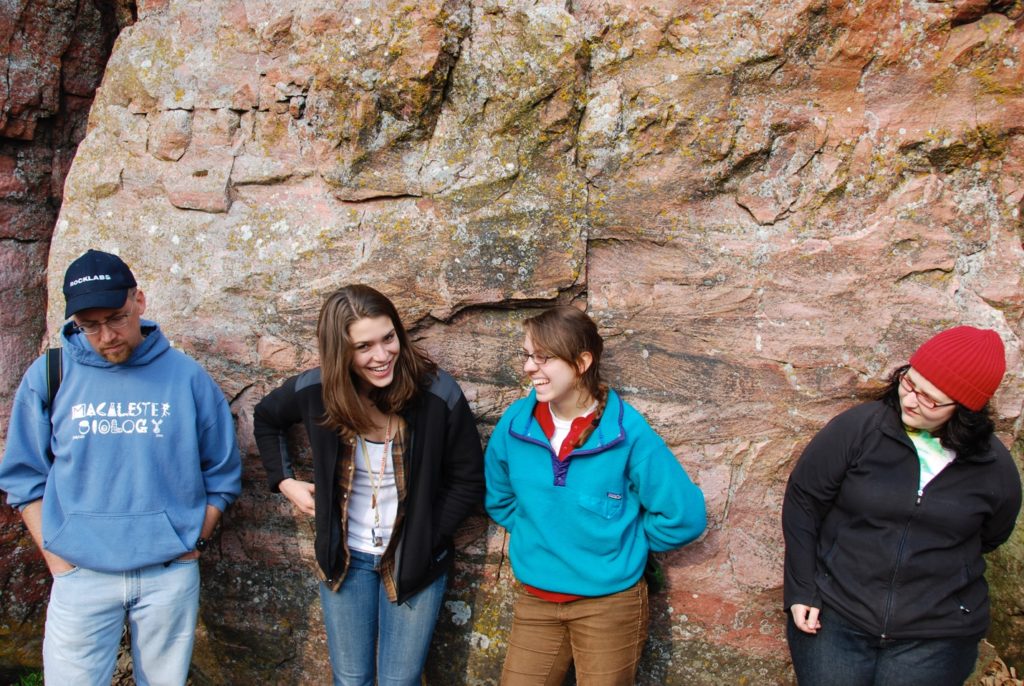 people leaning against a rock