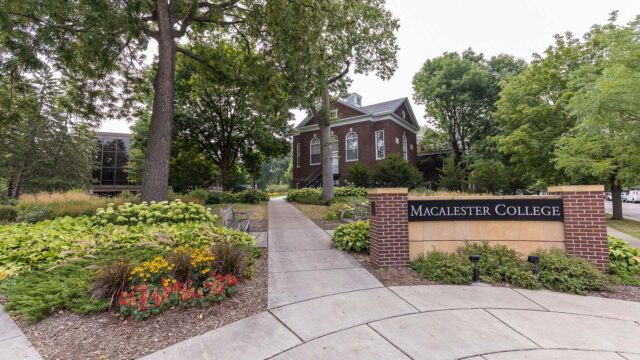 A shot of the Macalester Campus sign with Old Main in the background