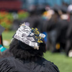 A close-up of a graduation cap decorated with printed selfies and stickers reading "GM 2024"