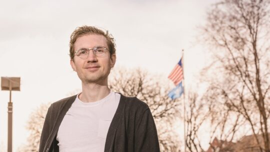 Charlie Birge ’15 photographed outside with an American flag in the background