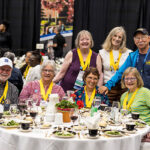 Nine alumni wearing Golden Scots medals sit together at a table