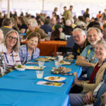 Seven Reunion attendees eating lunch together at a table pose for a picture