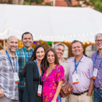 Seven Reunion attendees stand outside a tent and smile for the camera
