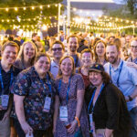 Eleven Reunion attendees pose for a picture under some string lights at a nighttime event
