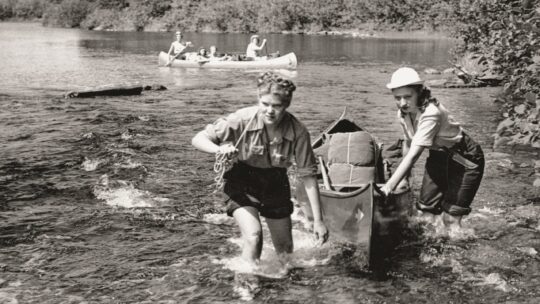 Dorothy Holstrom Schneider ’49 and classmate pull a canoe on a lake.