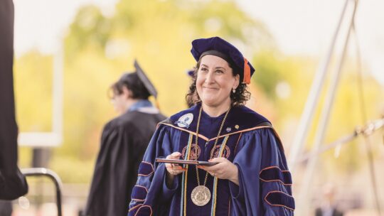 President Suzanne Rivera at commencement, wearing a cap and gown.