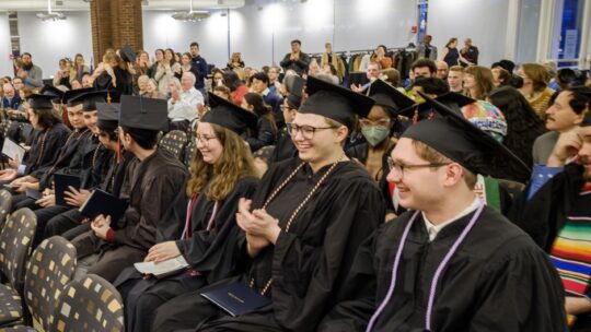 Students smile and clap at December graduation.