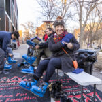 President Rivera shows off the new Mac athletics mittens while putting on a pair of ice skates at the Brighter campaign launch event.