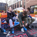 Two Mac students sit and put on ice skates at the Brighter campaign launch event.