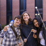 Three Mac students pose together with smore sticks in their hands at the Brighter campaign launch event.