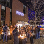 Mac community members stay warm outside of JWall as they huddle around fires during the Brighter campaign launch event.