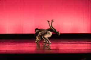 Two crouching dancers flip another over their backs