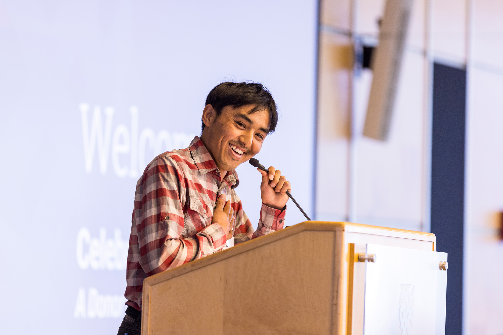 A student places their hand over their heart as they speak at the podium at an event.